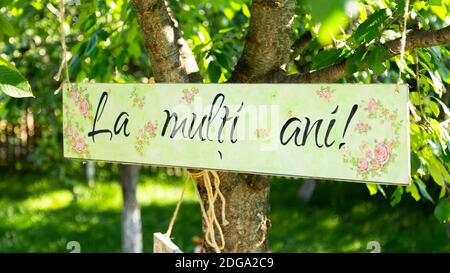 Ein Brett auf einem Baum mit 'Happy Birthday' in rumänischer Sprache Darauf geschrieben Stockfoto