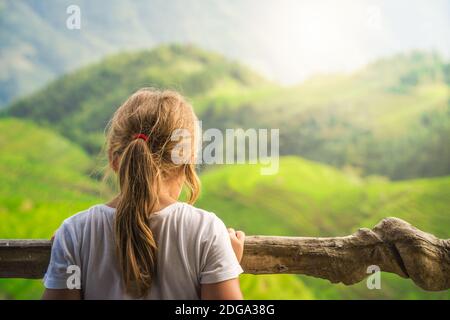 Niedliches junges Mädchen, das auf einem Aussichtspunkt der neun Drachen und fünf Tiger steht und die stufenförmigen Longji-Reisterrassen, Pingan Village, nördliches GUI, bewundert Stockfoto