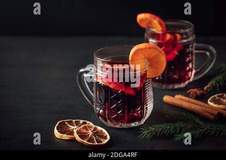 Traditioneller heißer Glühwein zu Weihnachten. Heißes Getränk mit Gewürzen in einer Glasschale auf dunklem Hintergrund. Stockfoto