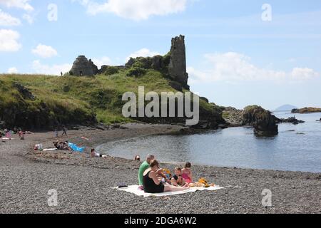 Dunure Castle, Dunure, Ayrshire, Schottland, Großbritannien. Dunure war der uralte Sitz der Familie Kennedy, die traditionell die Herren von Carrick und schließlich die Grafen von Cassillis waren.Ein Familienpicknick am steinigen Strand vor dem Schloss. Das Schloss und das Dorf werden im Outlander-Franchise genutzt Stockfoto