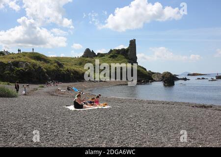 Dunure Castle, Dunure, Ayrshire, Schottland, Großbritannien. Dunure war der uralte Sitz der Familie Kennedy, die traditionell die Herren von Carrick und schließlich die Grafen von Cassillis waren.Ein Familienpicknick am steinigen Strand vor dem Schloss. Das Schloss und das Dorf werden im Outlander-Franchise genutzt Stockfoto