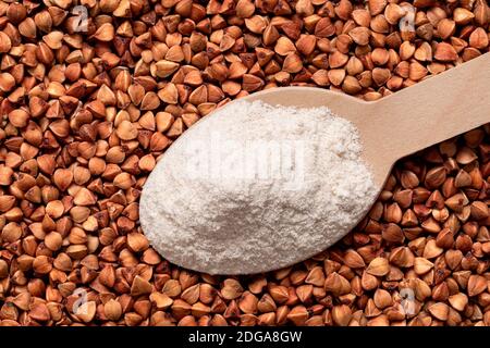 Löffel Buchweizenmehl auf rohen gerösteten Buchweizen. Draufsicht. Stockfoto