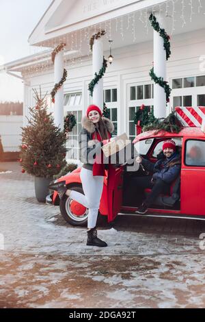 Junges Paar kauft Weihnachtsgeschenke für ihre Familie und nehmen Sie nach Hause in einem roten Auto Stockfoto
