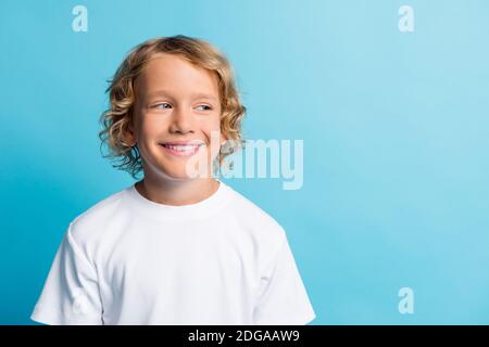 Foto von hübschen Jungen aussehen leeren Raum strahlend lächelnd tragen Weißes T-Shirt isoliert auf blauem Hintergrund Stockfoto