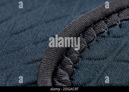 Makrohintergrund aus einer Naht auf einem Stoff in marineblauer Farbe, rhomboide Formen. Stockfoto