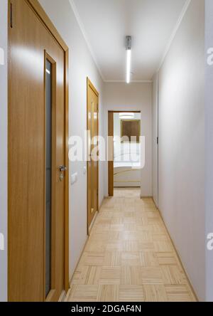 Modernes Interieur des schmalen Flurs in der Wohnung. Weiße Wände. Offene Tür zum Schlafzimmer. Stockfoto