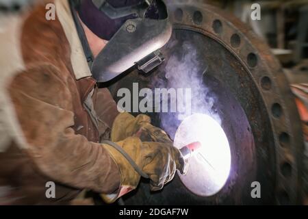 Schweißen arbeitet am Metallwärmetauscher mit manuellem Lichtbogenschweißen Stockfoto