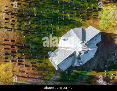 Weiße Kirche mit hohem Turm und einem alten Friedhof von oben gesehen. Stockfoto