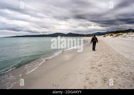 Im Urlaub allein in Kontakt mit der Natur zu finden - EIN Alleinreisender mit einem Rucksacktouristen spaziert bei Sonnenuntergang Oder Morgendämmerung entlang eines tropischen Strandes in der Nähe der s Stockfoto