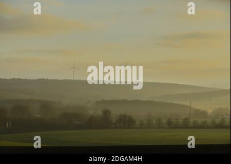 Fulda, Deutschland. Dezember 2020. Blick vom Fuldaer Stadtteil Dietershan bei Sonnenaufgang auf die Höhen des Naturparks Hessische Rhön mit Windmühlen (l). Quelle: Andreas Arnold/dpa/Alamy Live News Stockfoto