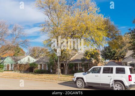 Geparktes Auto vor Vorstadthäusern, umgeben von bunten Herbstlaub in der Nähe von Dallas, Texas, Amerika. Ruhige Wohnstraße mit Tempolimit Stockfoto