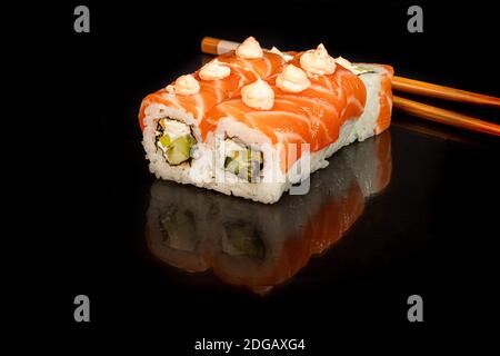 Sushi setzt Uramaki, California, Philadelphia, auf einen weißen Teller. Festliches Neujahrskonzept. Vor einem dunklen reflektierenden Hintergrund. Speicherplatz kopieren Stockfoto