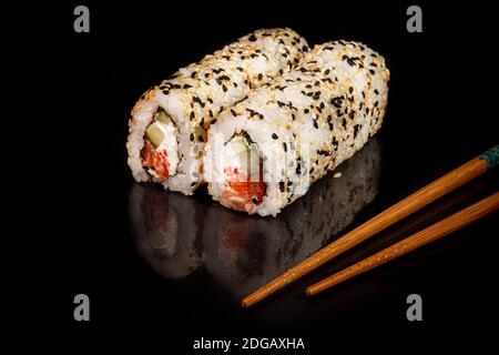 Sushi setzt Uramaki, California, Philadelphia, auf einen weißen Teller. Festliches Neujahrskonzept. Vor einem dunklen reflektierenden Hintergrund. Speicherplatz kopieren Stockfoto