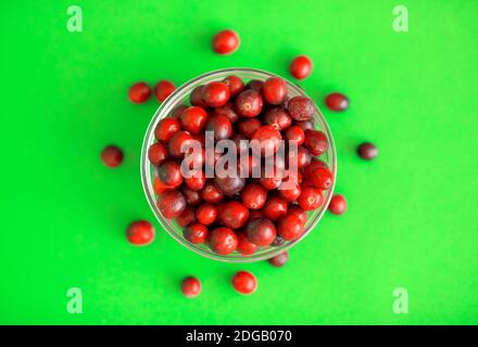 Frische rote Preiselbeeren in einer Glasschüssel auf grünem Hintergrund Stockfoto