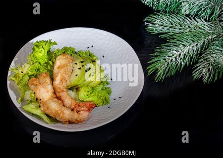 Avocado und King Garnelen Salat auf grünen Blättern. Festliches Dinner Neujahrs-Konzept. Gesunde Ernährung. Auf einem schwarzen reflektierenden Hintergrund. Speicherplatz kopieren. Stockfoto