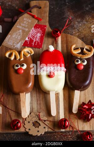 Сhocolate popsicle. Weihnachtskonzept. Schokoladeneis auf einem Stock mit einem weihnachtlichen Hirschgesicht mit einer süßen roten Nase. Weihnachtsbacken. Vorbereitungen f Stockfoto