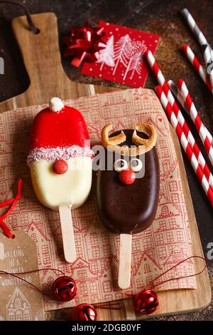 Сhocolate popsicle. Weihnachtskonzept. Schokoladeneis auf einem Stock mit einem weihnachtlichen Hirschgesicht mit einer süßen roten Nase. Weihnachtsbacken. Vorbereitungen f Stockfoto