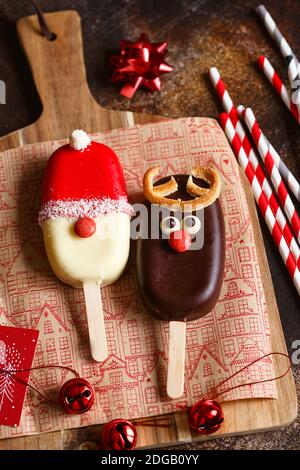 Сhocolate popsicle. Weihnachtskonzept. Schokoladeneis auf einem Stock mit einem weihnachtlichen Hirschgesicht mit einer süßen roten Nase. Weihnachtsbacken. Vorbereitungen f Stockfoto