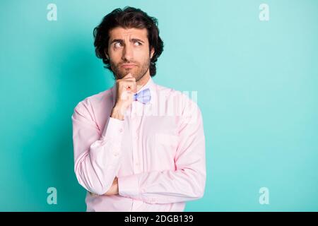 Foto von gesinntem jungen Mann, der sein Kinn berührt, sieht leer aus Raum gekleidet formalwear violette Krawatte isoliert auf türkisfarbenem Hintergrund Stockfoto