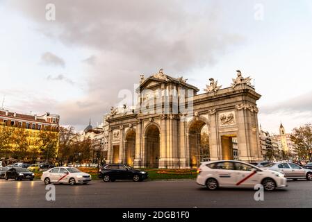 Puerta de Alcala bei Sonnenuntergang in Madrid. Blick während der Weihnachtszeit mit Bewegung verschwommen Autos Stockfoto