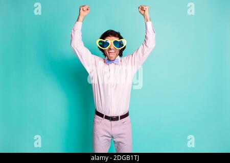 Portrait des Jubeljubels junger Kerl Heben Sie die Fäuste tragen Herz Shaped Sun specs isoliert auf türkisfarbenem Hintergrund Stockfoto