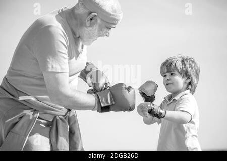 Vater trainiert seinen Sohn beim Boxen. Kleiner Junge Sportler beim Boxtraining mit Trainer. Schwarz und Weiß Stockfoto