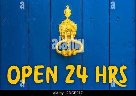 Die Worte Open 24 Hours Written on a Blue Door Mit einem Golden Door Knocker Stockfoto