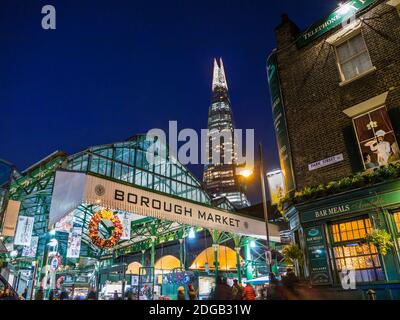 Borough Market Weihnachten Außenfassade Eingang & Weihnachtseinkäufer, Lichter Nacht mit Weihnachtskränze London Shard Tower hinter Southwark London UK Stockfoto