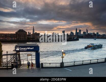 CANARY WHARF RB1 THAMES CLIPPER SONNENUNTERGANG IN LONDON Themse Clipper River Boat RB1 bei Sonnenuntergang Abfahrt vom Canary Wharf Pier, Richtung Upstream, Shard und London Financial City District in b/g Canary Wharf Thames Clipper London UK Stockfoto