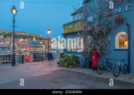 Blick auf das Restaurant am Flussufer und den roten Briefkasten in der Abenddämmerung, Whitby, Yorkshire, England, Großbritannien, Europa Stockfoto