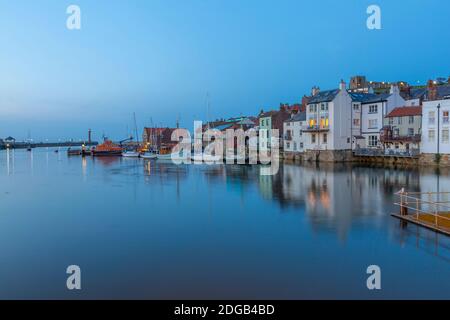 Blick auf Boote und Häuser, die in River Esk in der Abenddämmerung spiegeln, Whitby, Yorkshire, England, Großbritannien, Europa Stockfoto