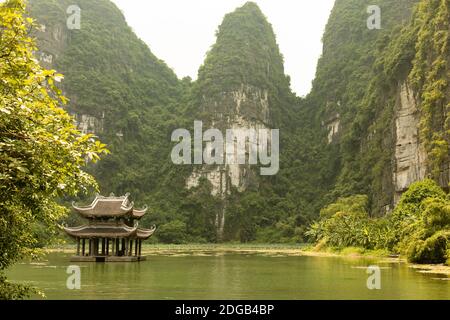 Ein Boot in der Nähe eines malerischen Tempels auf dem Wasser in Trang an, in einem natürlichen Komplex zum UNESCO-Weltkulturerbe erklärt, in Ninh Binh, Vietnam. Stockfoto