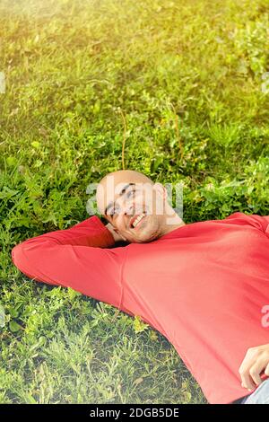 Junger Mann, der sich entspannt und im Park spazierengeht, das Leben genießt und am Nachmittag lächelt Stockfoto