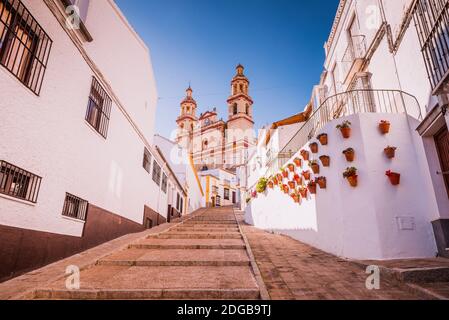 Calle calzada - Calle Calzada, typisch andalusische Straße mit Töpfen, im Hintergrund die Kirche unserer Lieben Frau von der Menschwerdung. Olvera, Cádiz, Andal Stockfoto