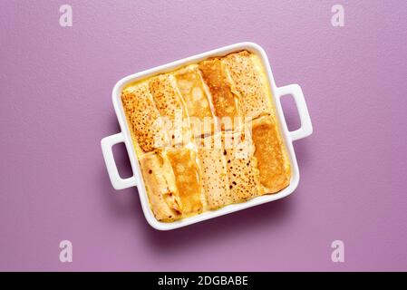 Blick von oben mit französischen Pfannkuchen Brötchen gefüllt mit Quark gebacken in einem Tablett mit süßer Sahne-Sauce. Köstliche Crepes-Rolle mit Käse gefüllt. Stockfoto