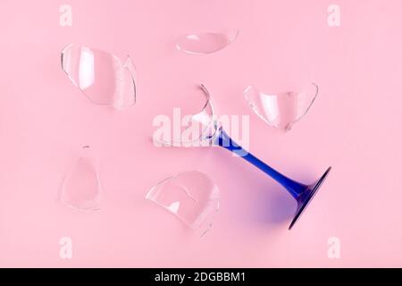 Nahaufnahme von oben auf gebrochenem Glas Weinkelch mit blauem Bein auf rosa Hintergrund. Horizontale Ausrichtung, selektiver Fokus. Stockfoto