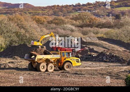 Pontypridd, Wales - November 2020: Dumper Truck bewegt eine Bodenladung auf dem Gelände einer neuen Wohnsiedlung. Im Hintergrund ist ein Bagger. Stockfoto