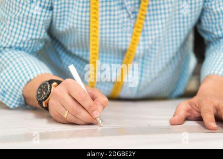 Schneiderhände markieren Zeichnung auf Bastelpapier für die Herstellung von Mustern. Stockfoto