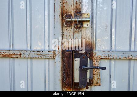 Eiserner rostiger Zaun mit einem Schloss. Weiße Wellblech oder Zink Textur Oberfläche oder galvanisieren Stahl in der vertikalen Linie Hintergrund Stockfoto