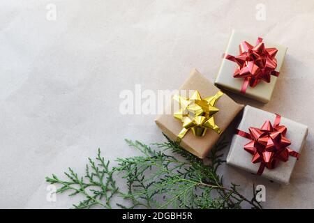 DIY Weihnachtsgeschenkboxen mit Schleifen zu Hause. Die Schachteln mit den Geschenken auf dem Hintergrund des handwerklichen Papiers und des Zweiges der Tanne Stockfoto