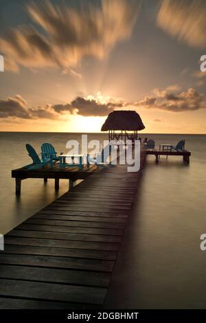 Pier mit Palapa am Karibischen Meer bei Sonnenaufgang, Caye Caulker Pier, Belize Stockfoto