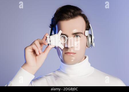 Cyborg man in Kopfhörer Einstellung digitale Augenlinse isoliert auf Violett Stockfoto