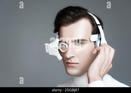 Cyborg man in digitalen Auge Objektiv Einstellung Kopfhörer isoliert auf Grau Stockfoto