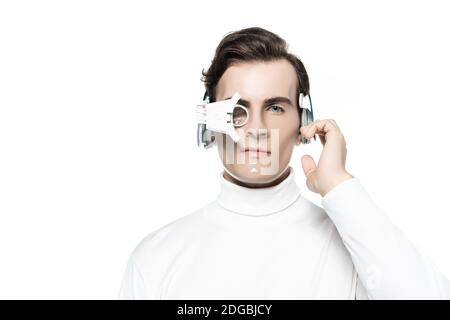 Cyborg im digitalen Auge Objektiv berühren Kopfhörer und betrachten Kamera auf Weiß isoliert Stockfoto