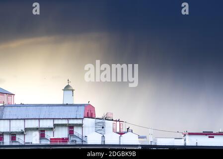 Dunkle Wolken und entfernter Regen umrahmt Britannia Pier an einem launischen Winternachmittag - Great Yarmouth, Norfolk (UK) Stockfoto