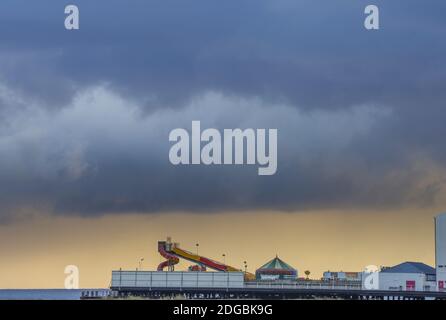 Dunkle Wolken und entfernter Regen umrahmt Britannia Pier an einem launischen Winternachmittag - Great Yarmouth, Norfolk (UK) Stockfoto