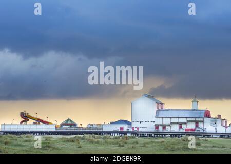 Dunkle Wolken und entfernter Regen umrahmt Britannia Pier an einem launischen Winternachmittag - Great Yarmouth, Norfolk (UK) Stockfoto