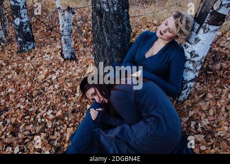 Porträt zweier Frauen, die in einem Wald sitzen und sich an einen Baum lehnen, Russland Stockfoto