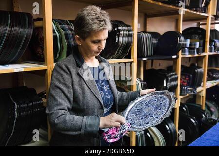 Moskau, Russland. Dezember 2020. Ein Arbeiter wischt den Staub von einem handdekorierten Tablett in der Zhostovo dekorative Malerei Fabrik, in der Region Moskau, Russland, am 8. Dezember 2020. Zhostovo ist ein russisches Volkskunstzentrum, das für seine bemalten Tabletts berühmt ist, die mit hellen Blumensträuchern verziert sind. Quelle: Maxim Chernavsky/Xinhua/Alamy Live News Stockfoto