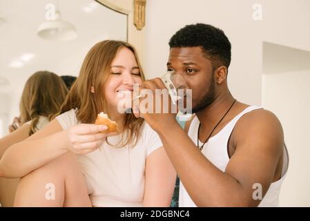 Gemischtes Rennpaar, das ein Croissant mit Marmelade isst und trinkt Ein Glas Milch Stockfoto